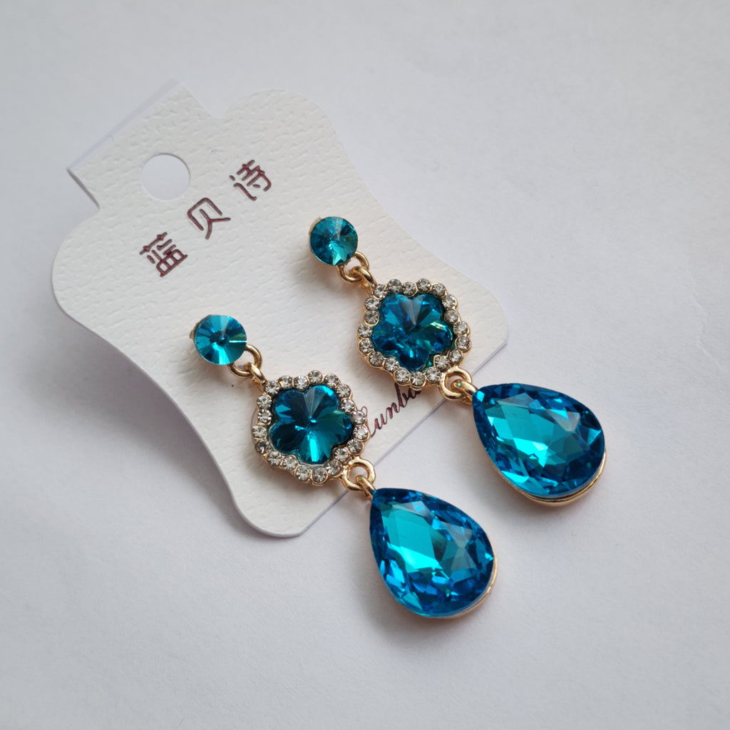 Blue teardrop earrings on a white background with a tag.
