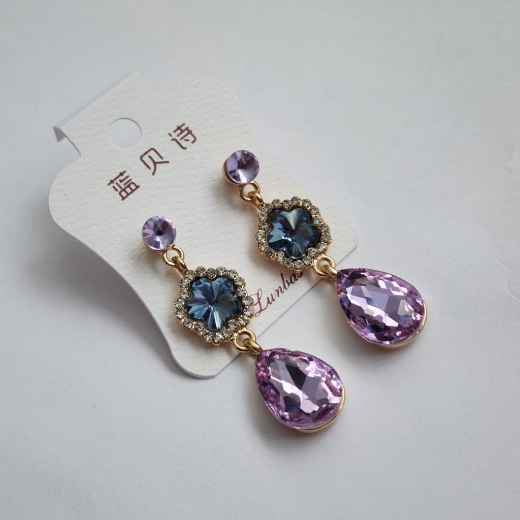 Pair of earrings with purple and blue gemstones on a white background