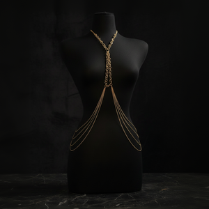 Gold chain body harness on a black mannequin against a dark background