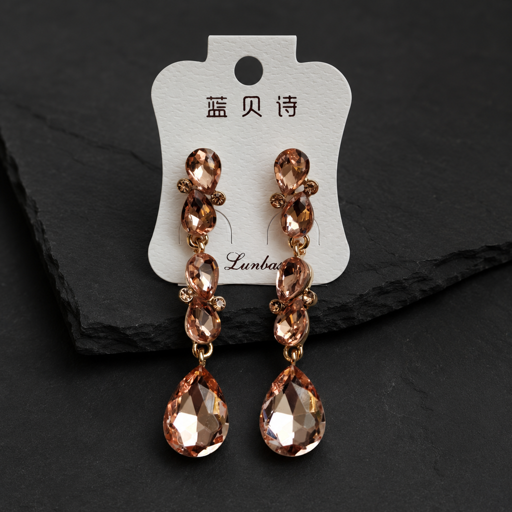 Pair of brown crystal earrings on a branded card against a dark background